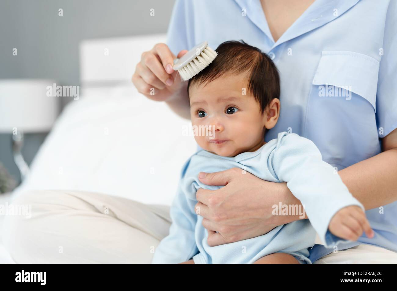 mother combing her newborn baby hair on a bed Stock Photo Alamy