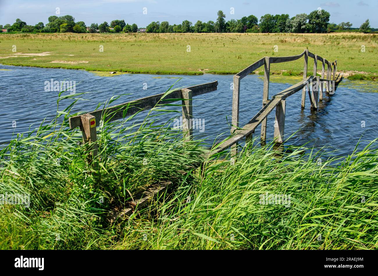 Old and somewhat shaky wooden footbridge across a creek in the polders between Rockanje and Tinte in the Netherlands Stock Photo