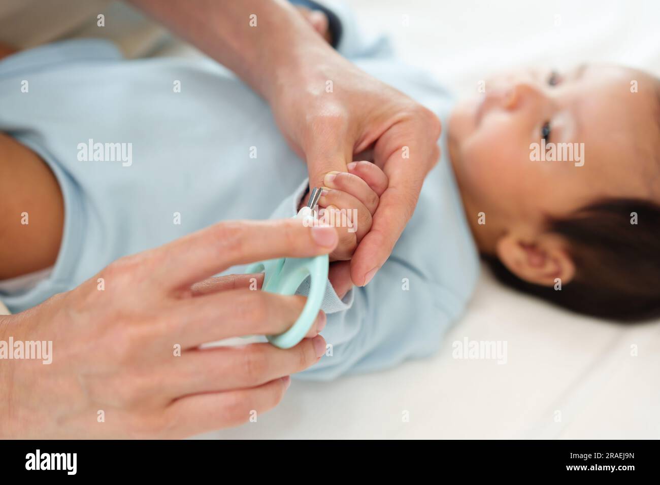 mother cutting newborn baby's hand fingernails with nail scissors Stock
