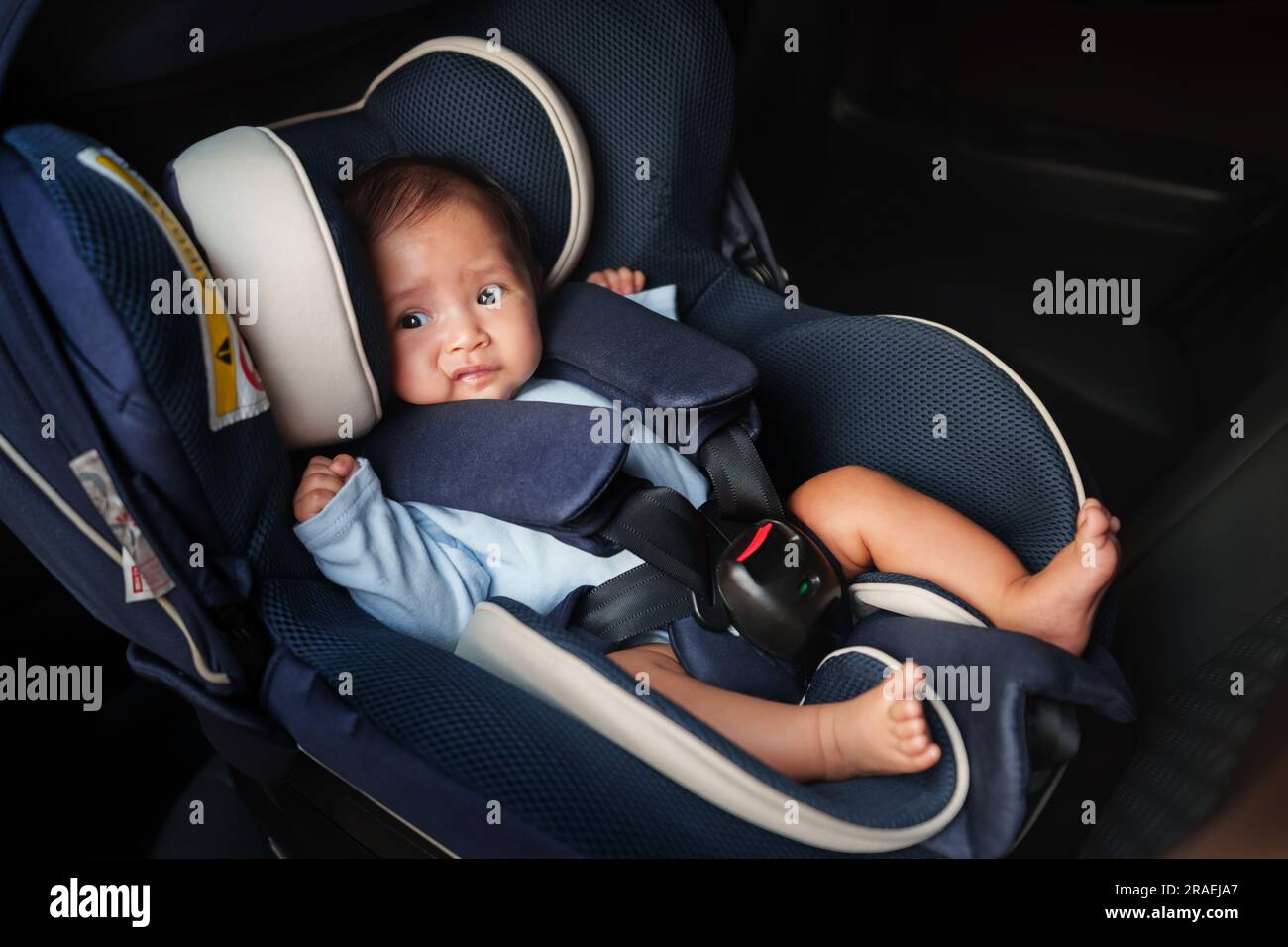 newborn baby crying while sitting in an infant car seat, safety chair