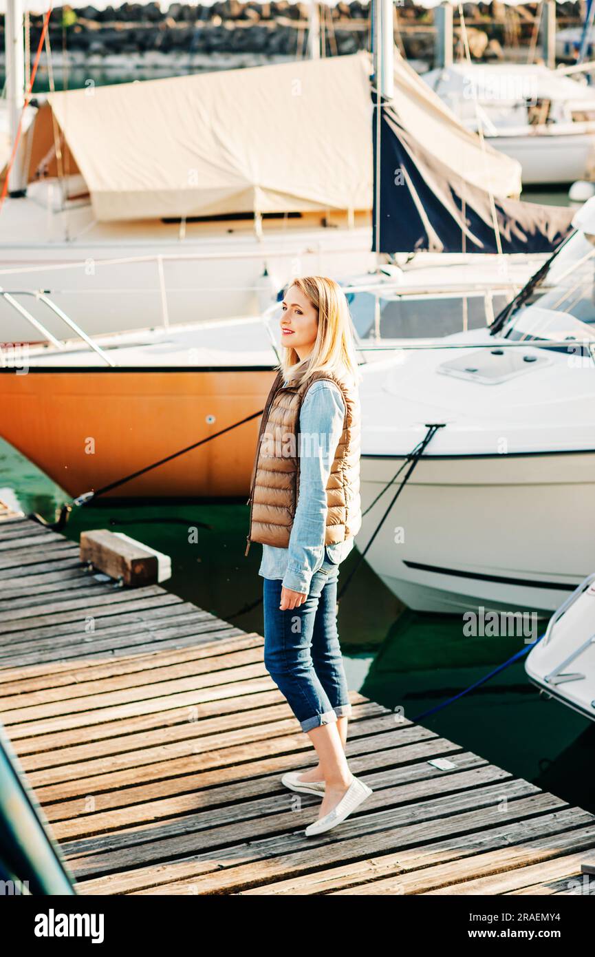 Outdoor fashion portrait of beautiful young woman posing by the lake in ...