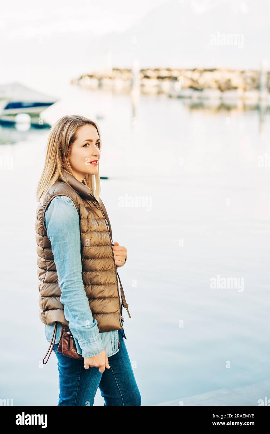 Outdoor fashion portrait of beautiful young woman posing by the lake in ...