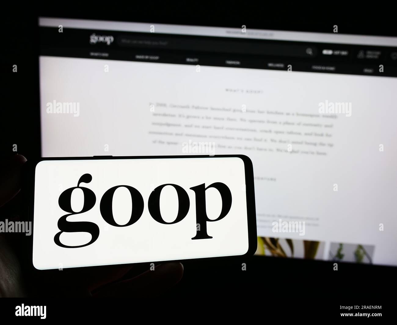 Person holding smartphone with logo of US publishing and e-commerce company Goop Inc. on screen in front of website. Focus on phone display. Stock Photo