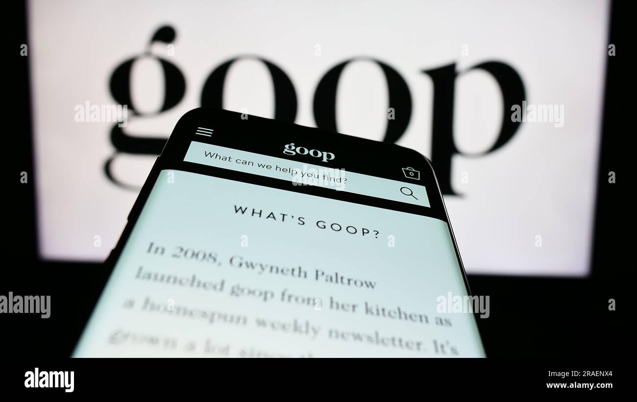 Smartphone with webpage of US publishing and e-commerce company Goop Inc. on screen in front of business logo. Focus on top-left of phone display. Stock Photo