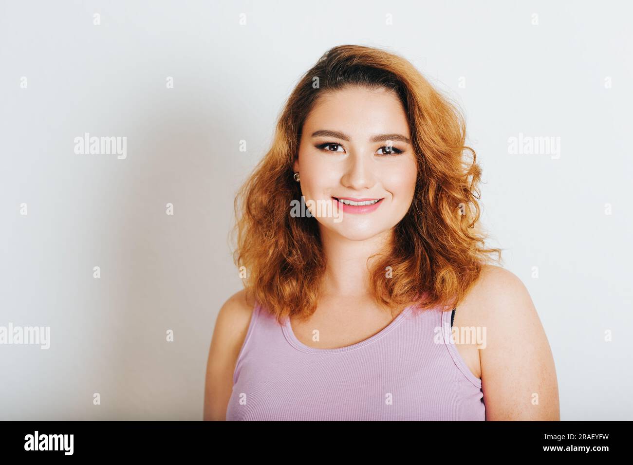 Studio shot of young 20-25 year old woman, bright red hair, pink lipstick Stock Photo