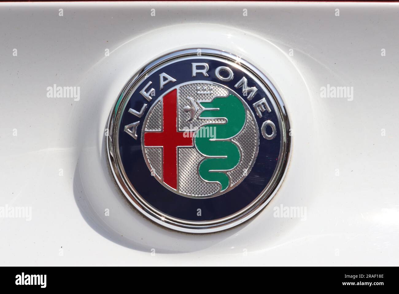 Newly refined Alfa Romeo three coloured automotive badge shown fitted to the rear of a white Alfa Romeo 4C sports car displayed at an Italian car day. Stock Photo