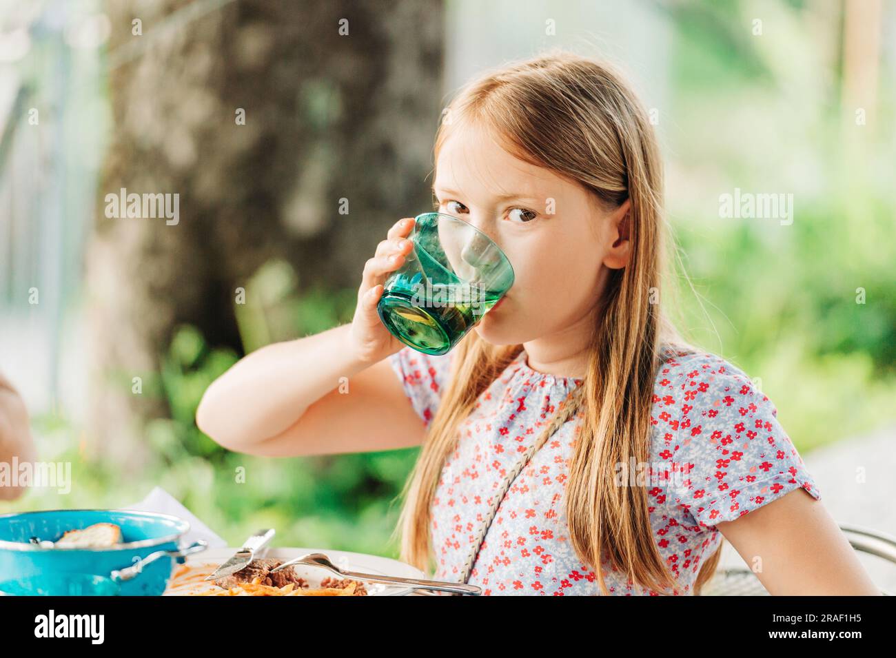 Little girl eating dinner on a terrace in outdoor restaurant Stock Photo