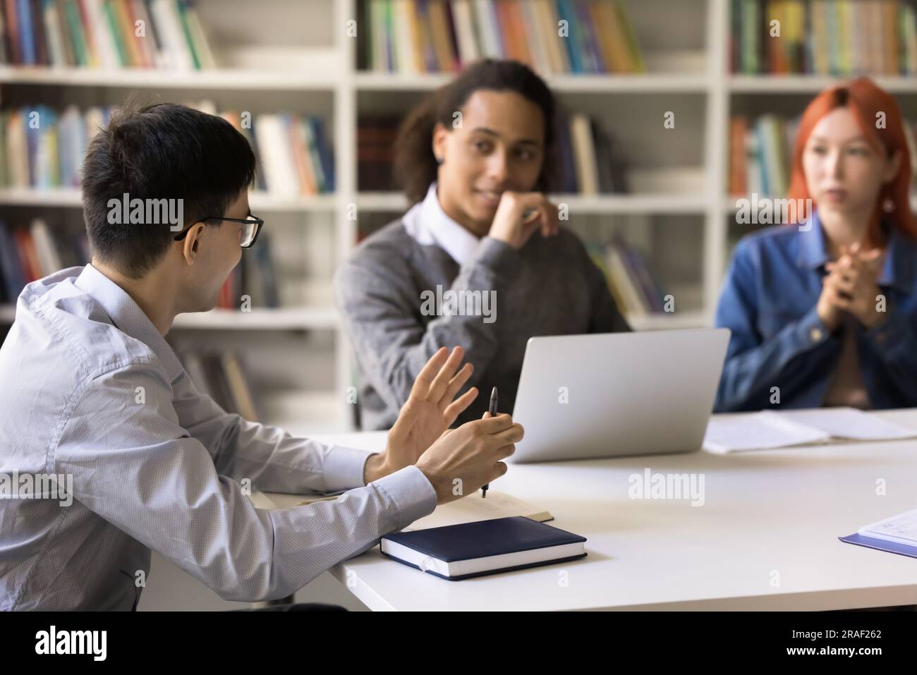 Smart student guy talking to friends in campus library Stock Photo - Alamy