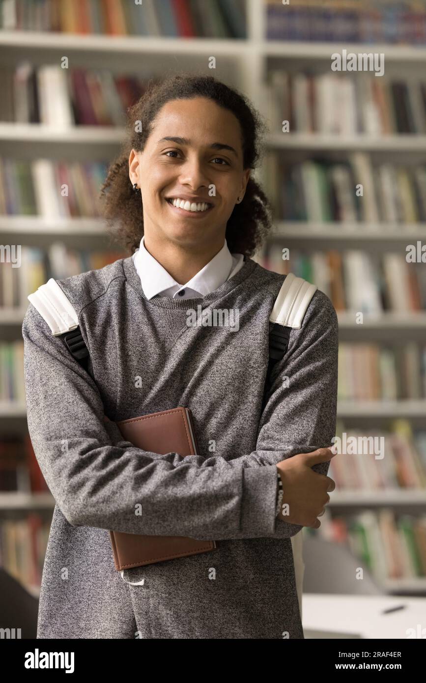 Confident Black student guy with backpack posing in library Stock Photo