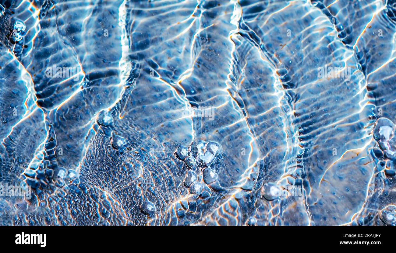 The windshield of a car with a light blue tint, in drops of rain