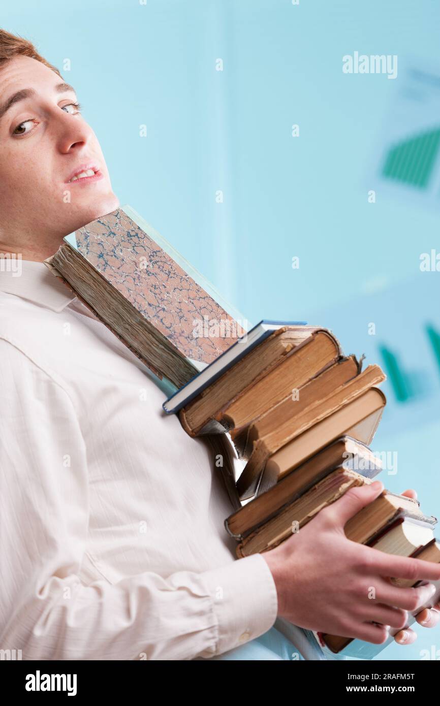 Stack of ancient-looking books held by a young man diagonally. Blurred ...