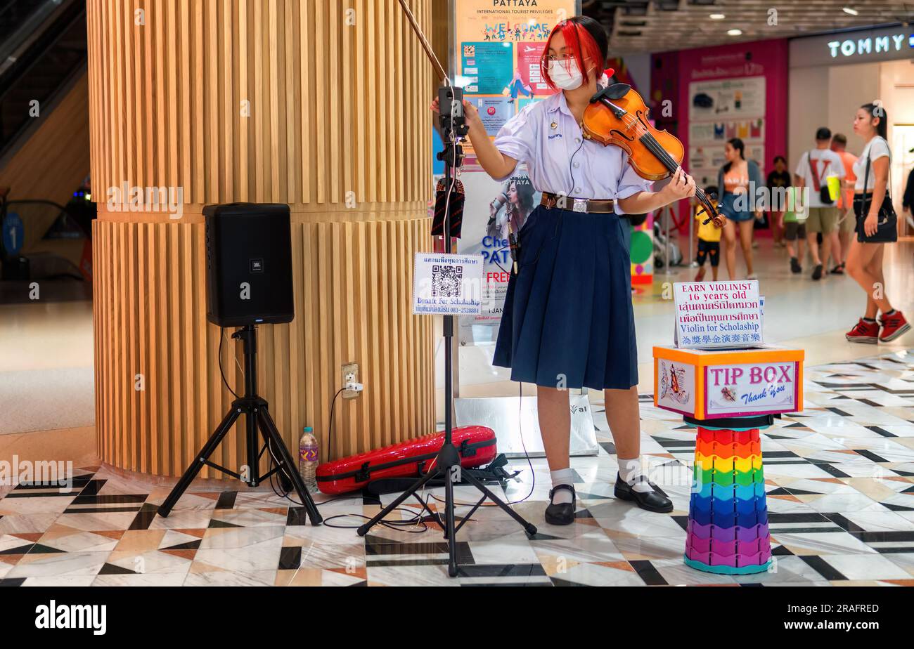 Pattaya,Thailand - March 24,2023: Second Road A young Thai woman with red and black hair was playing the violin in the Central Festival shopping mall. Stock Photo