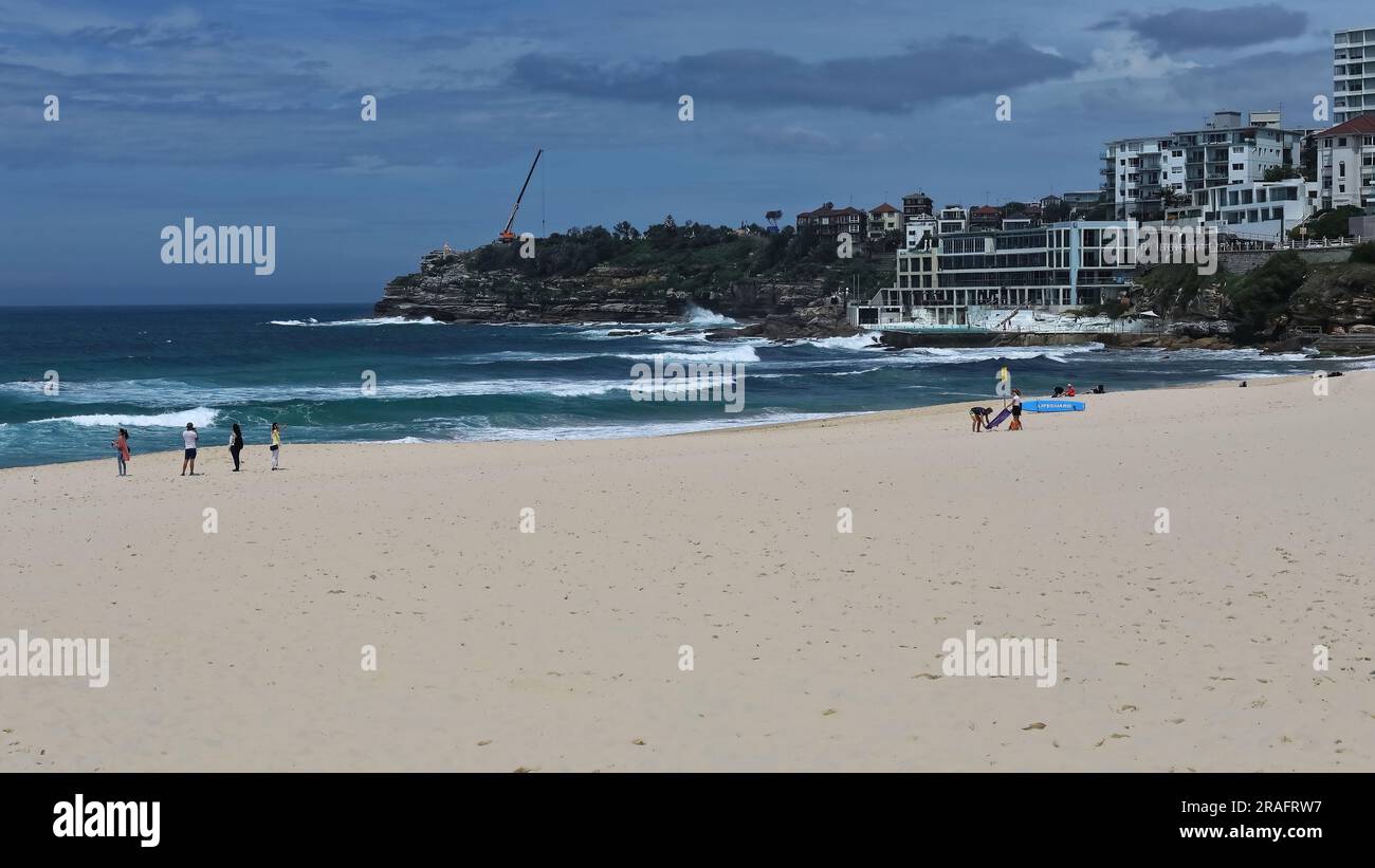 723 Tourist beachgoers on the Bondi Beach sand while surfers try to ...