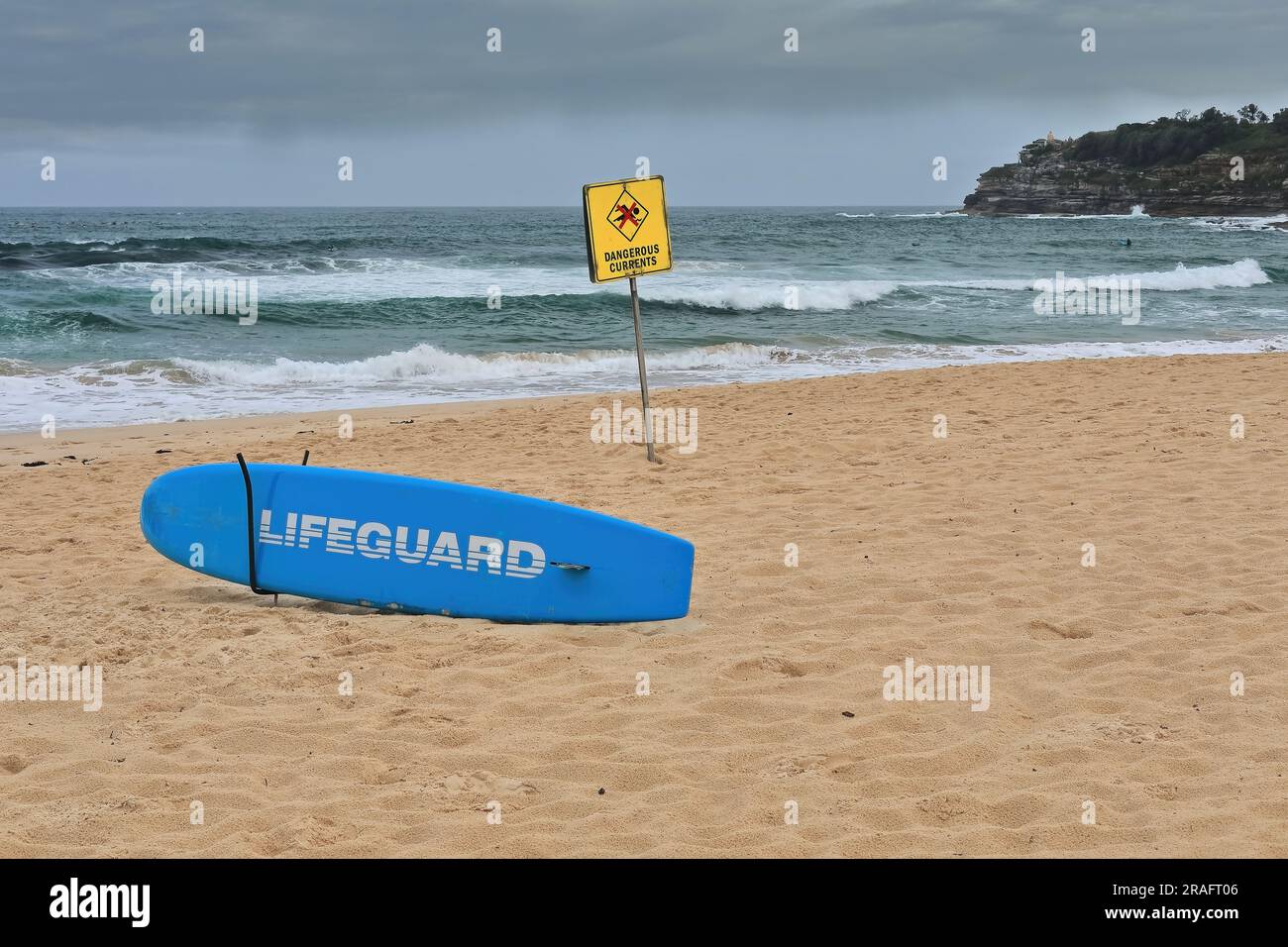 733 Yellow warning signpost and blue lifeguard surfboard on the sand at ...