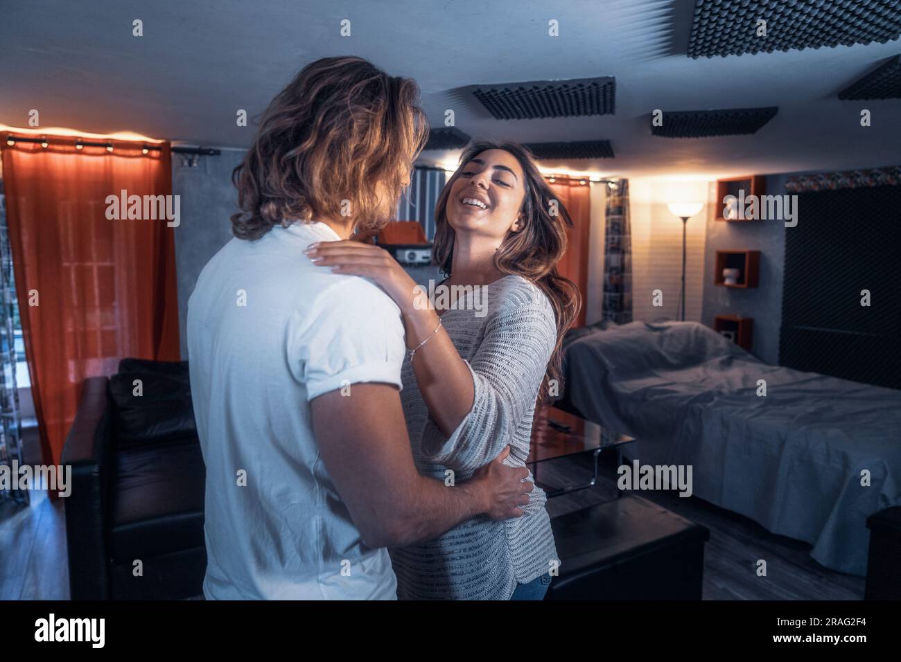Inside house couple shooting dancing in living room having fun, smiling and loughing - Yellow and blue light. Lovers shot dance flirting enjoying the Stock Photo