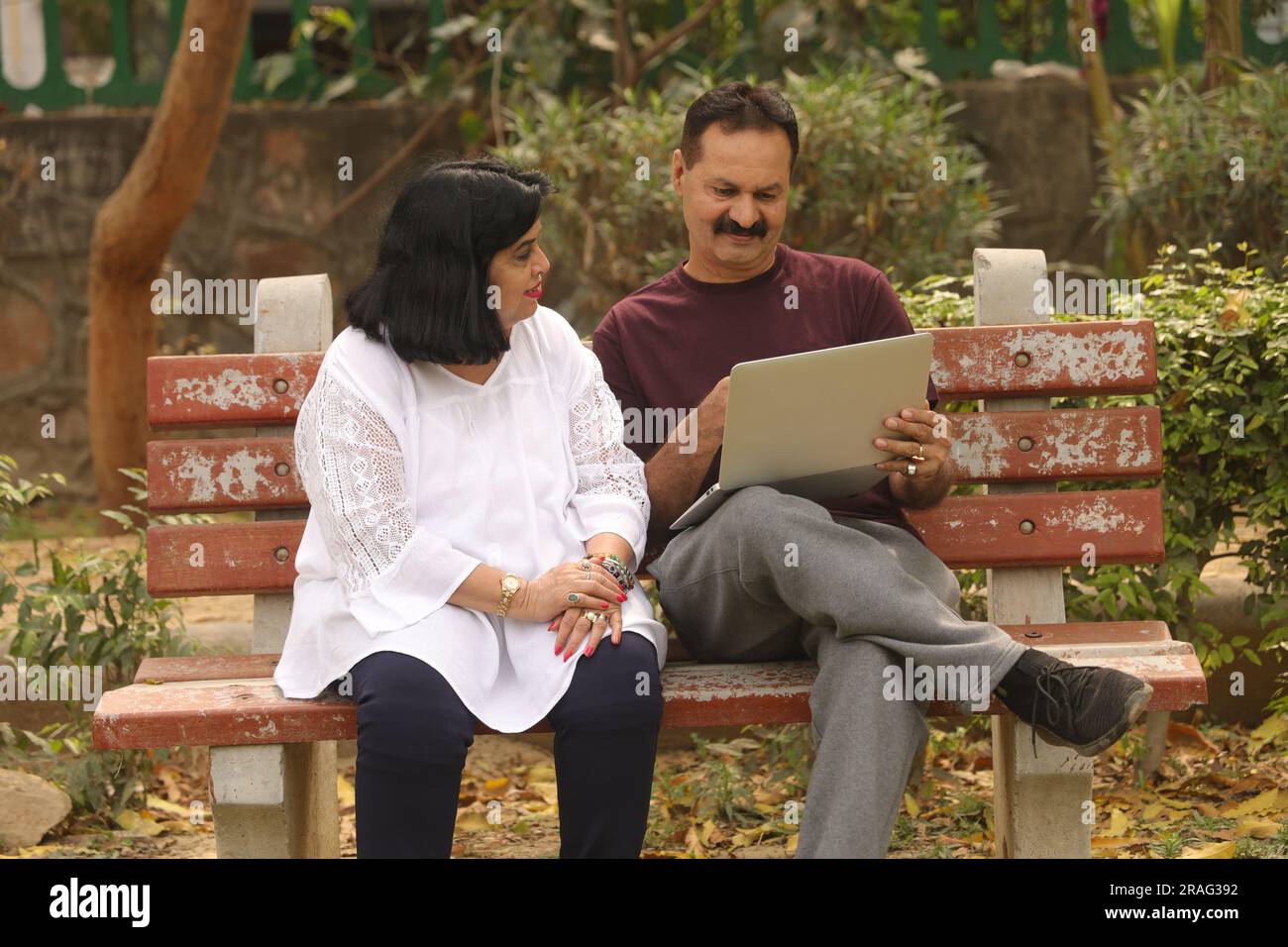 Beautiful Old Indian Happy couple sitting together in the park and having joyful moments of life. Planning for vacations together. Stock Photo