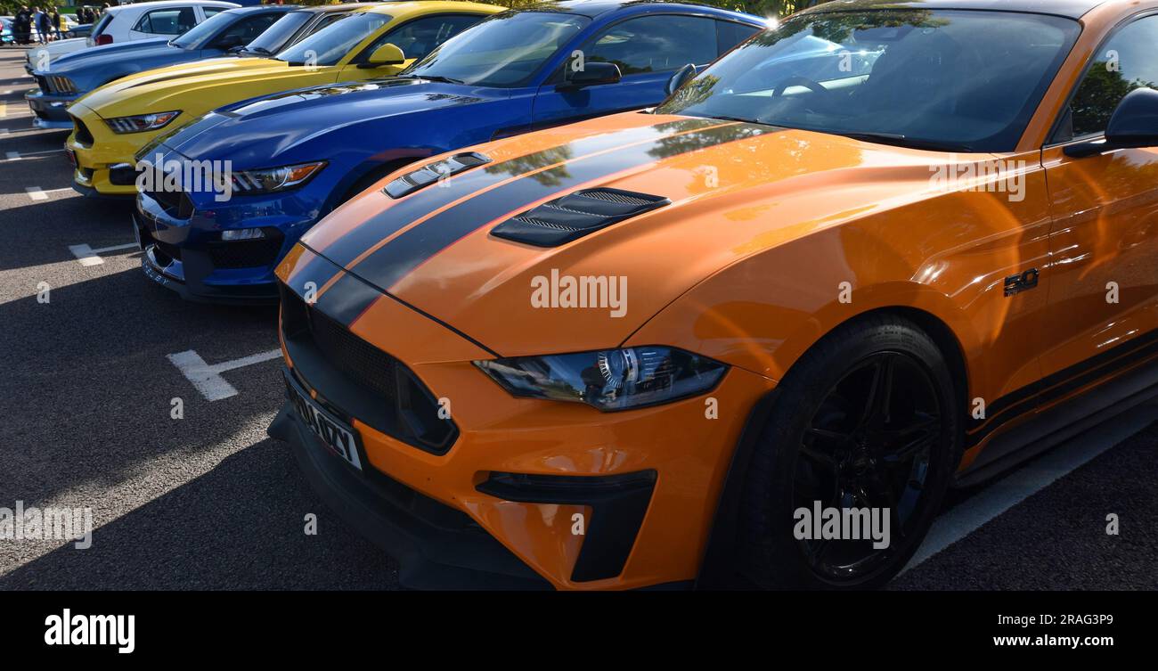 Three Ford Mustang Cars parked in a row  Orange Yellow and Blue Stock Photo