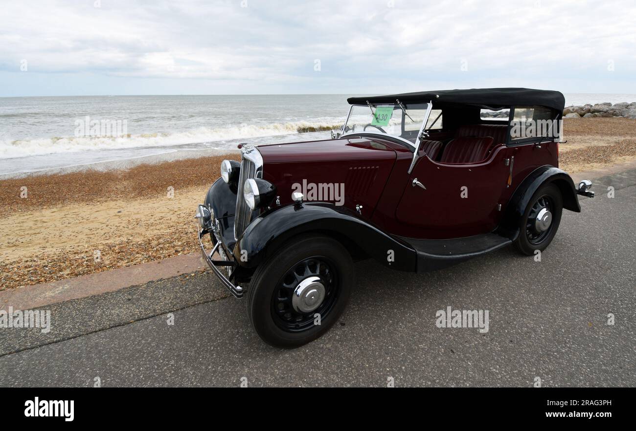 Vintage Red Morris 8 motor Car parked on seafront promenade beach and sea in background. Stock Photo