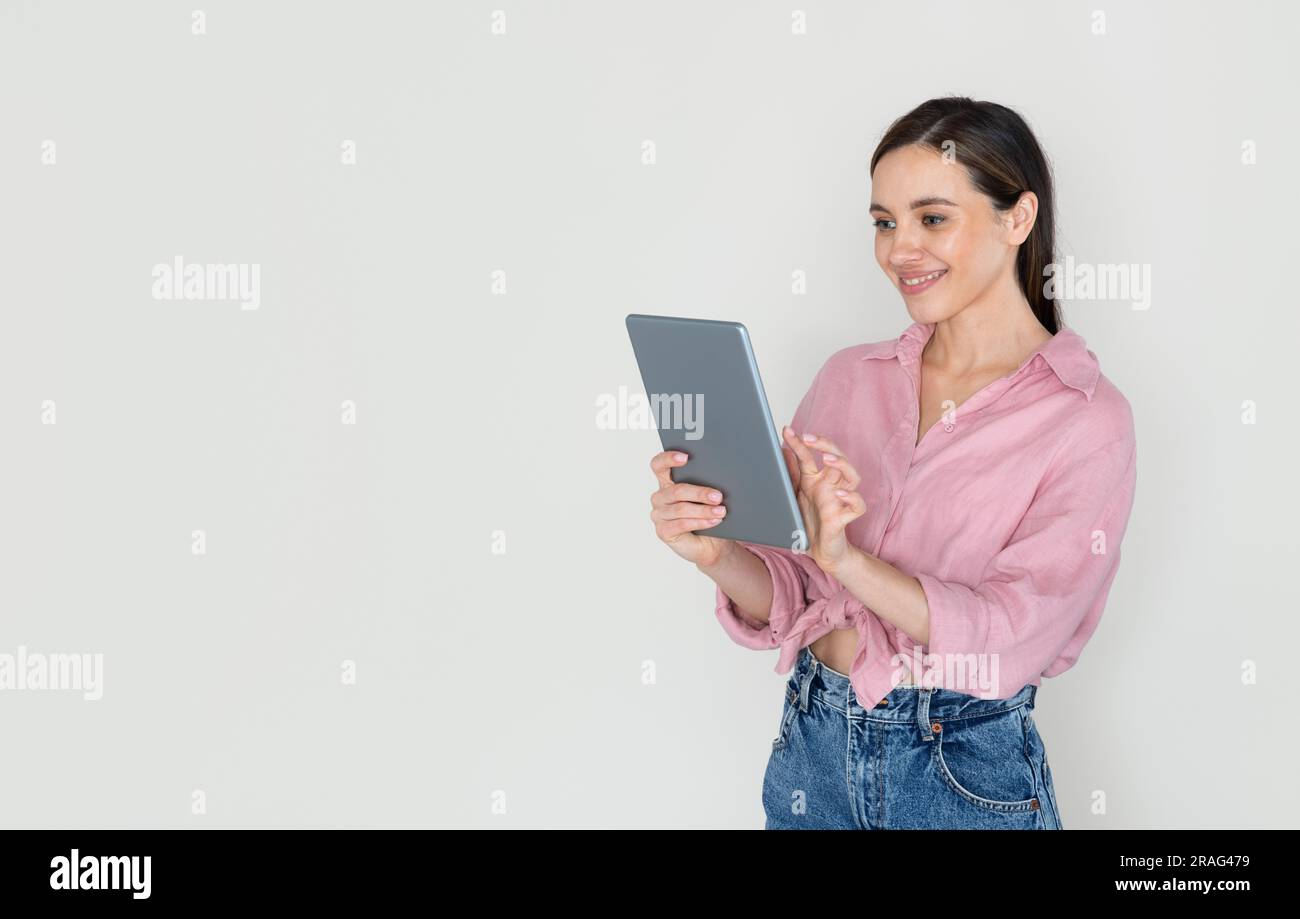 Cheerful young woman using digital tablet and smiling Stock Photo
