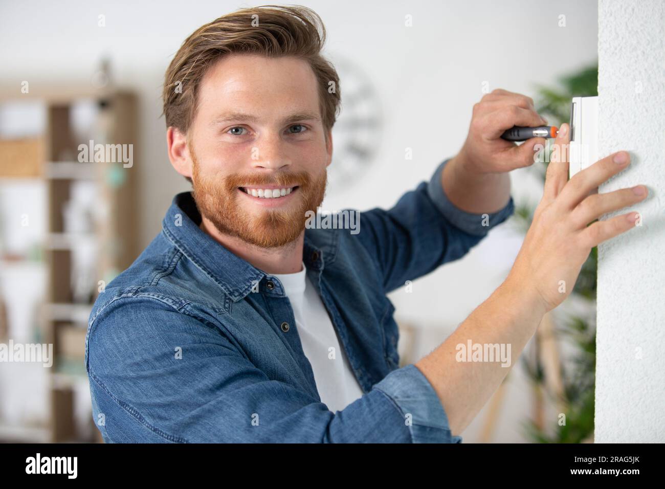 man hanging window curtain indoors Stock Photo