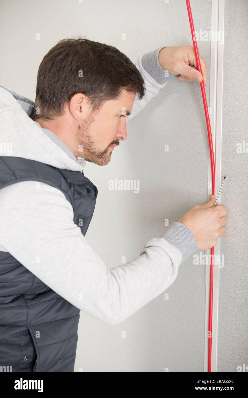 worker trying to install wires on the wall Stock Photo