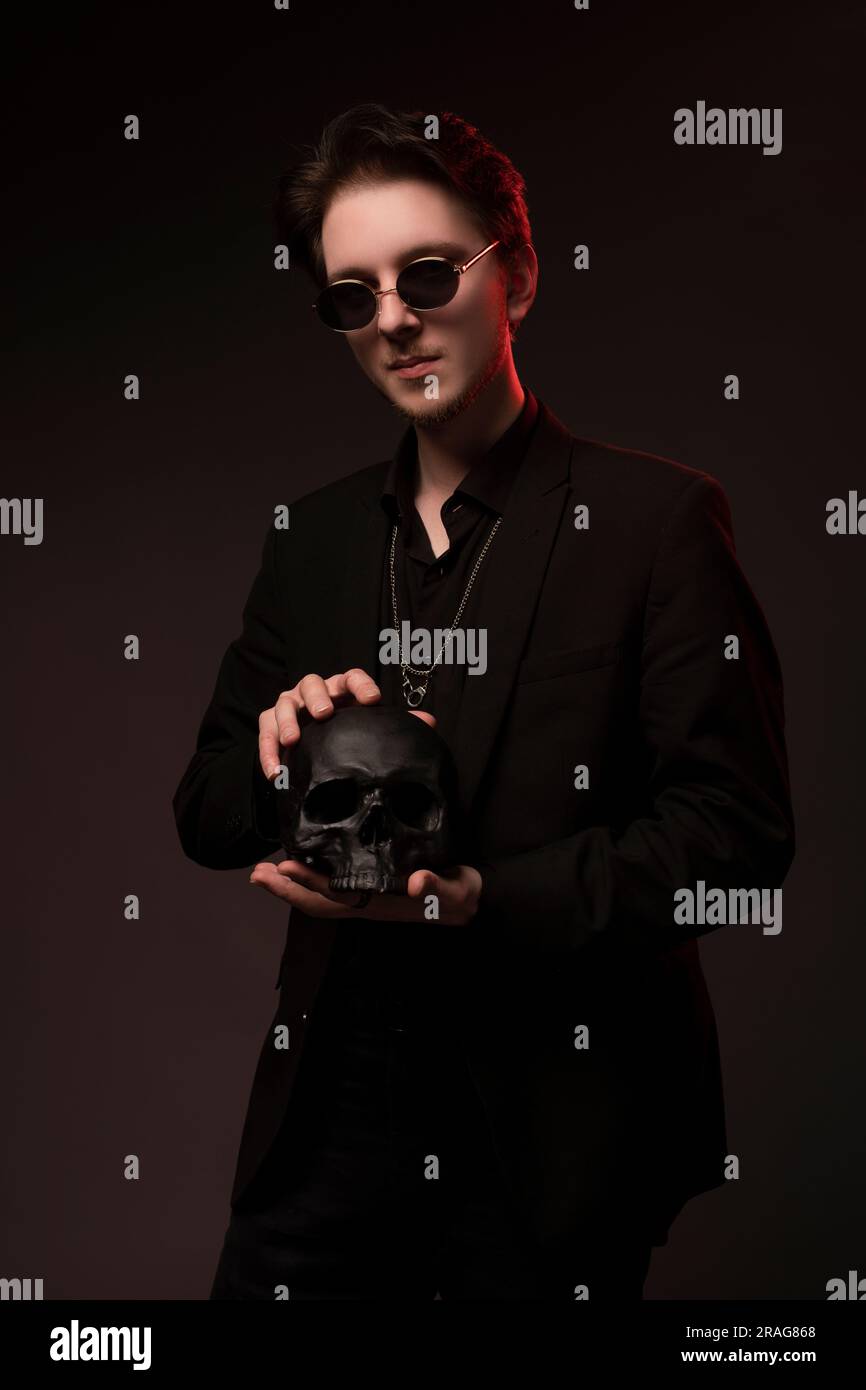 Man in black suit with skull in dark studio Stock Photo - Alamy