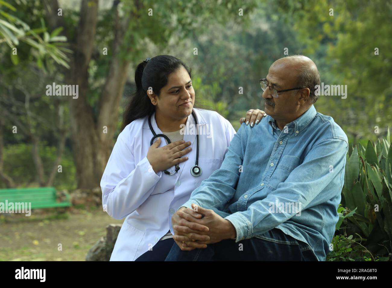 Female Indian doctor examining the senior patient in the city park in afternoon. Stock Photo