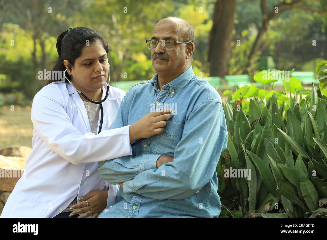 Female Indian doctor examining the senior patient in the city park in afternoon. Stock Photo