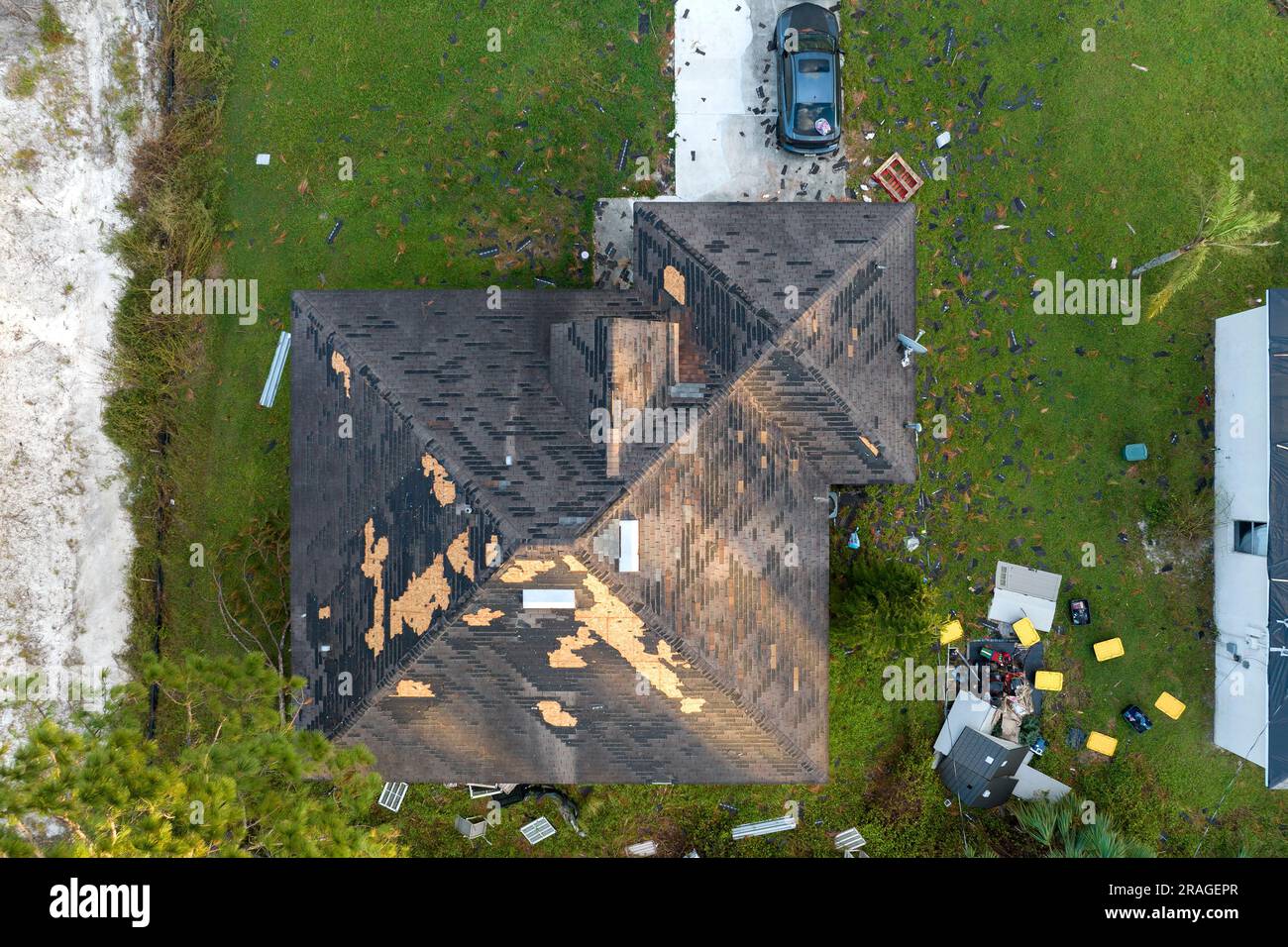 Consequences of natural disaster. Damaged house roof with missing shingles after hurricane Ian in Florida. Stock Photo