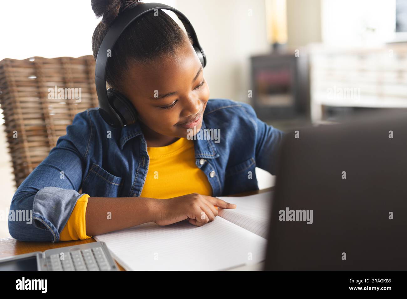 Happy african american girl sitting at table using laptop for online ...