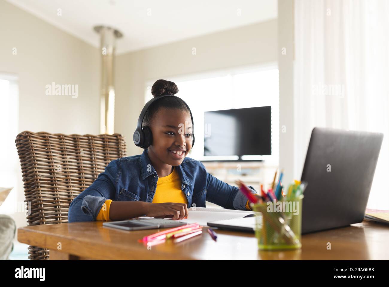 Happy african american girl sitting at table using laptop for online ...