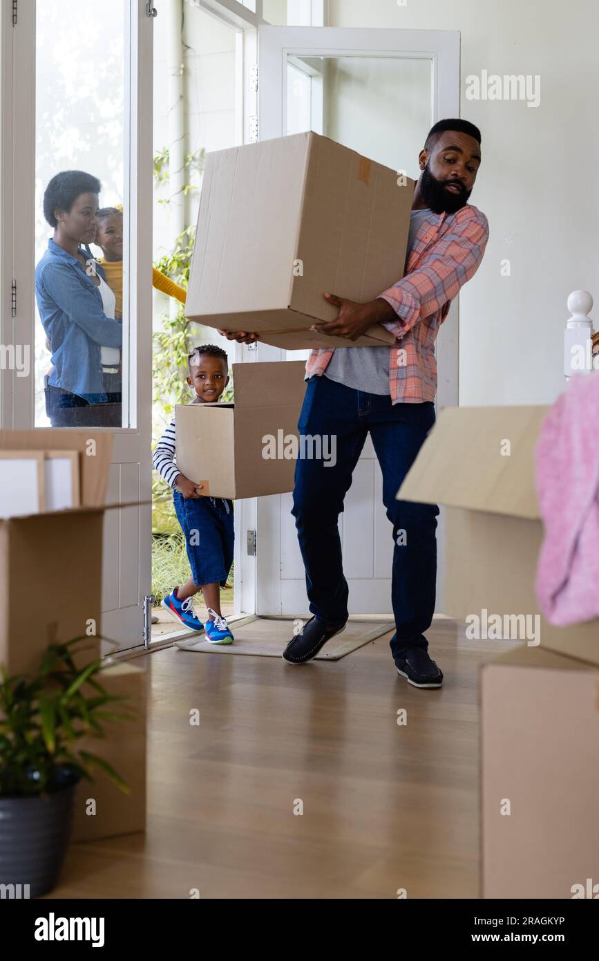 African american parents and children carrying cardboard boxes inside ...