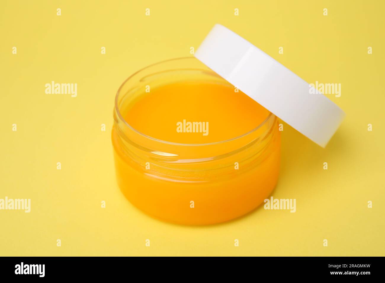 Open jar of petrolatum on yellow background Stock Photo