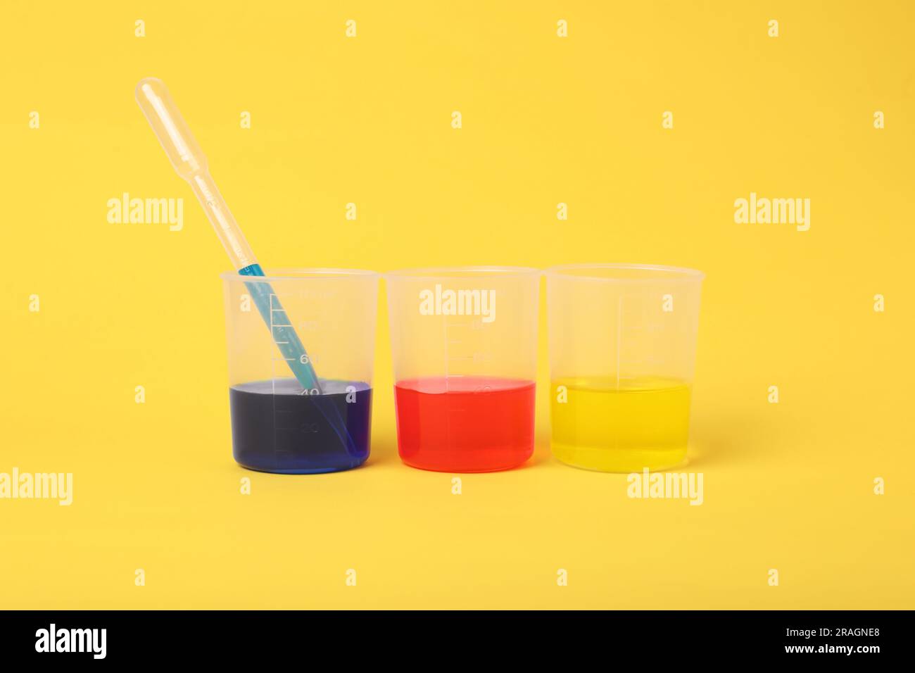 Beakers with colorful liquids on yellow background. Kids chemical experiment set Stock Photo