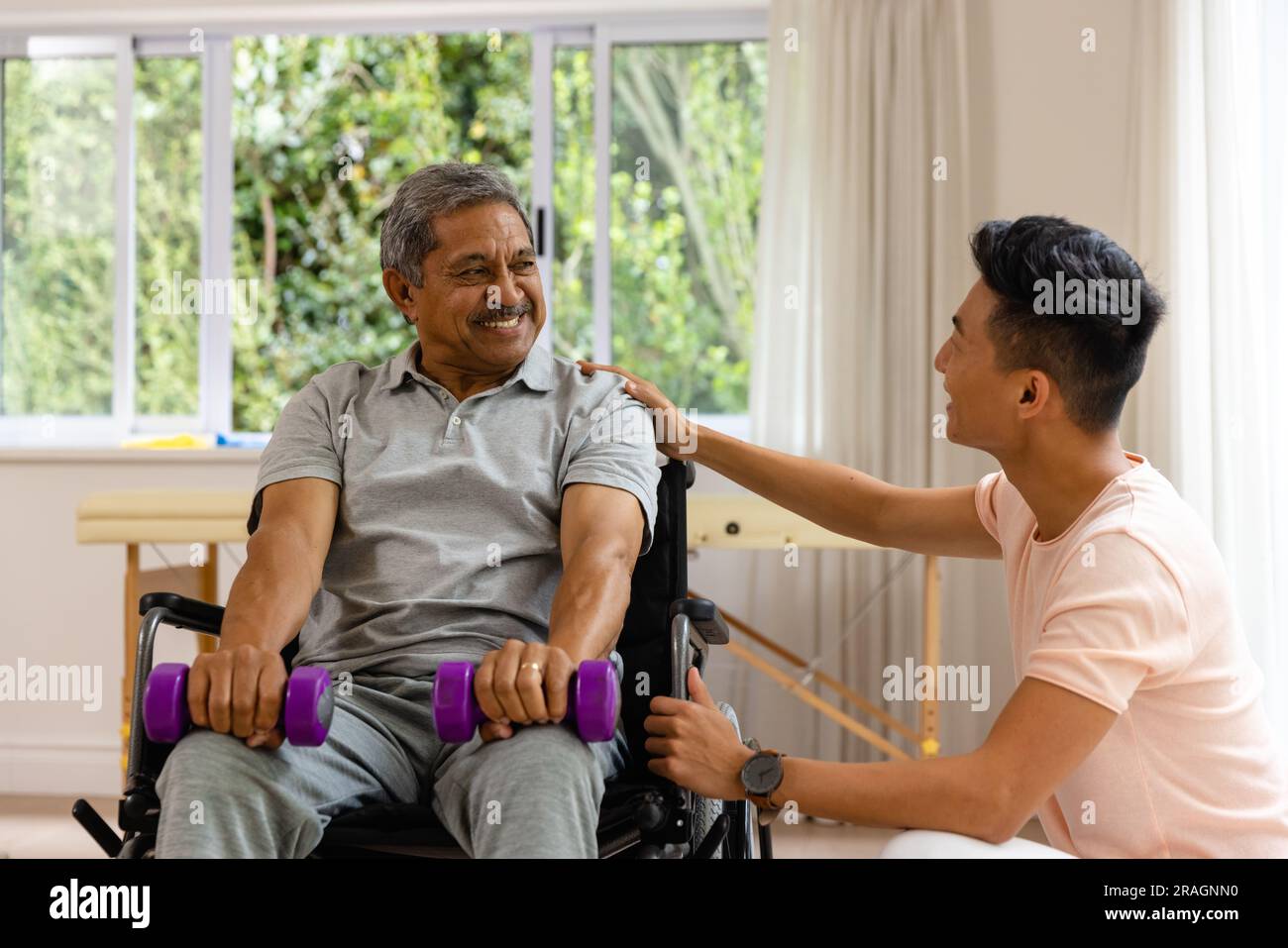 Happy diverse male physiotherapist advising and senior male patient in