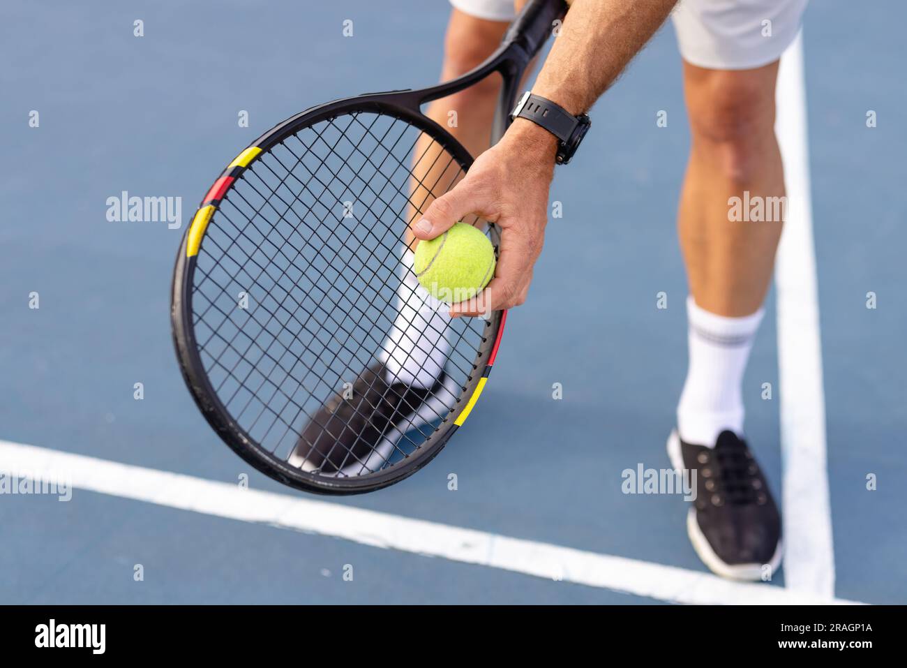 Low section of caucasian male tennis player holding tennis racket and ...