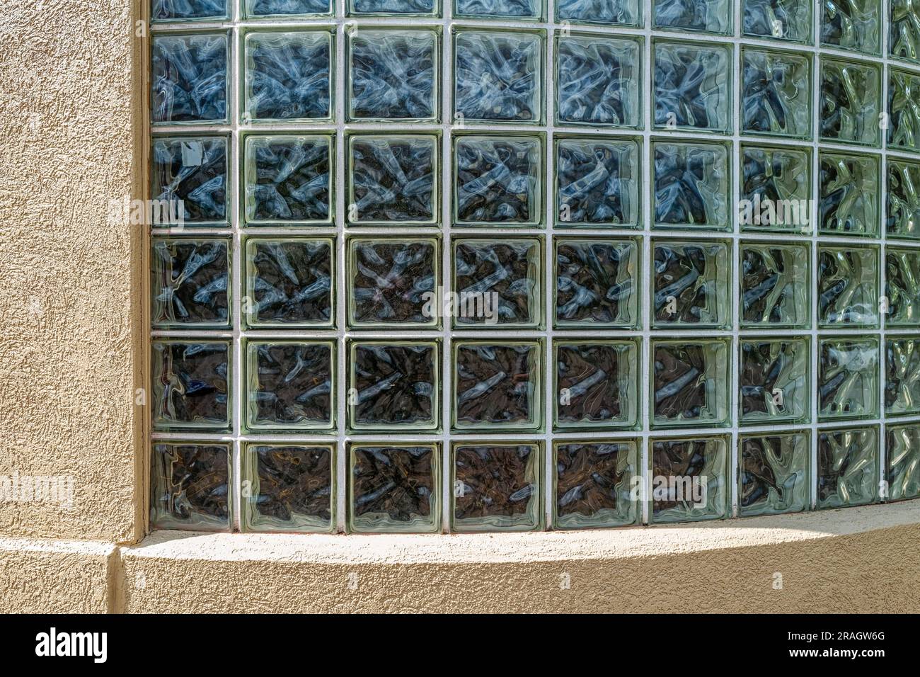 A curved glass block window on an exterior wall of a tan building Stock