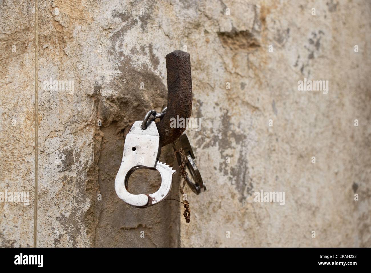 iron handcuffs hanging on a hook on the wall of the house close-up Stock Photo