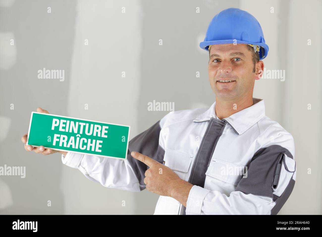 workman holding sign saying wet paint in french Stock Photo Alamy