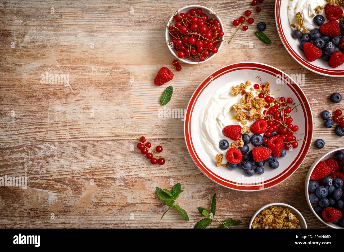 Yogurt with berries on wooden background. White plain greek yogurt with fresh berries and granola, top view. Healthy food, breakfast menu Stock Photo