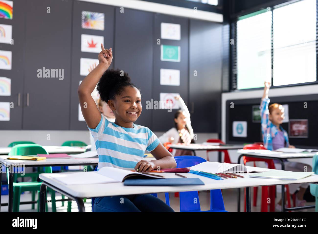 Smiling african american girl raising hand in elementary school ...