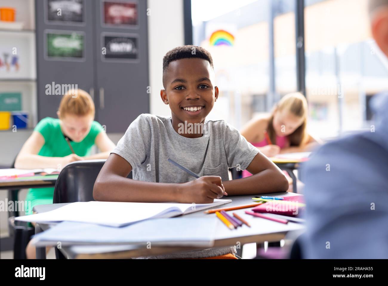 Portrait of smiling african american schoolboy working at his desk in ...