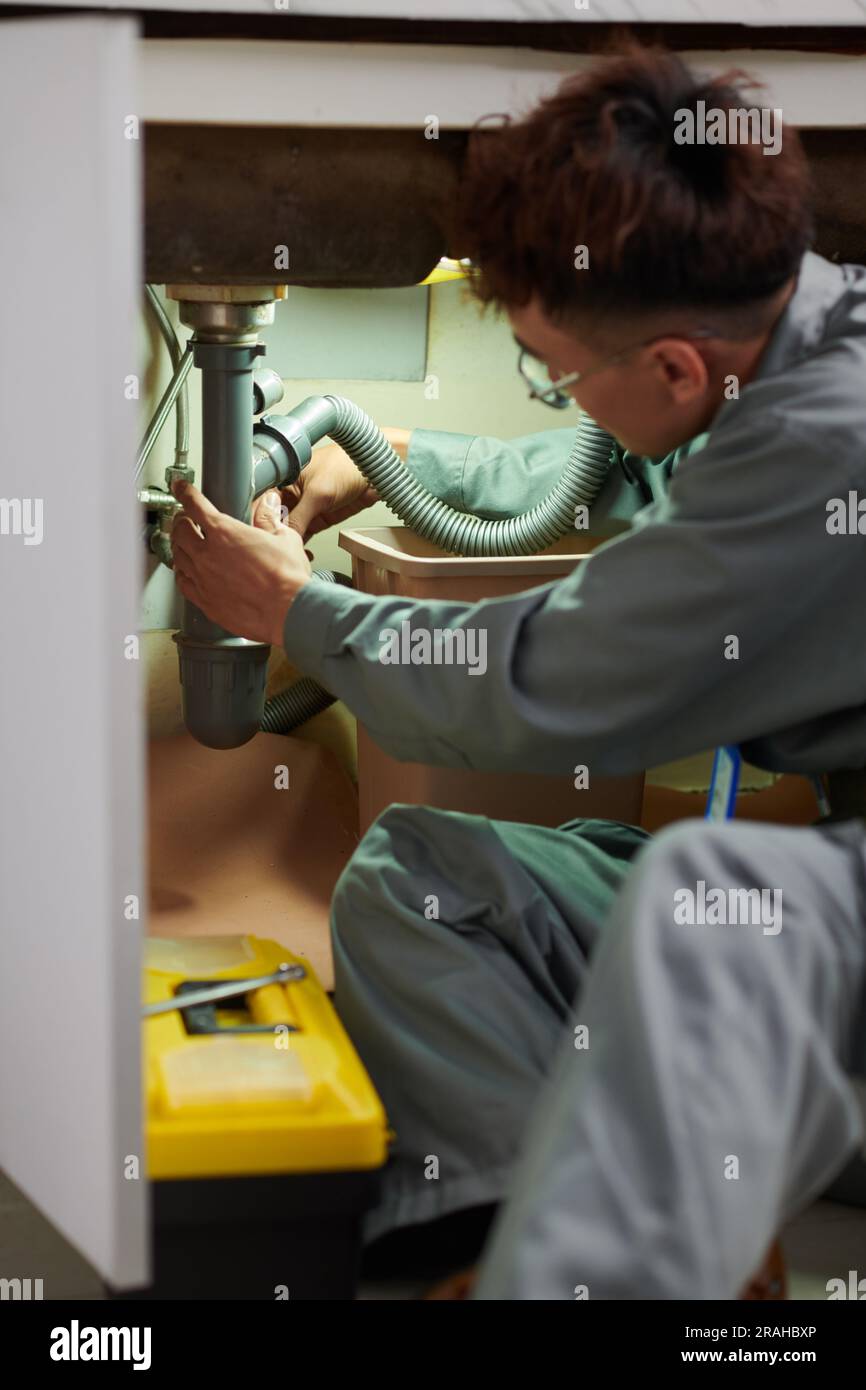 Plumber unclogging kitchen sink, household service Stock Photo