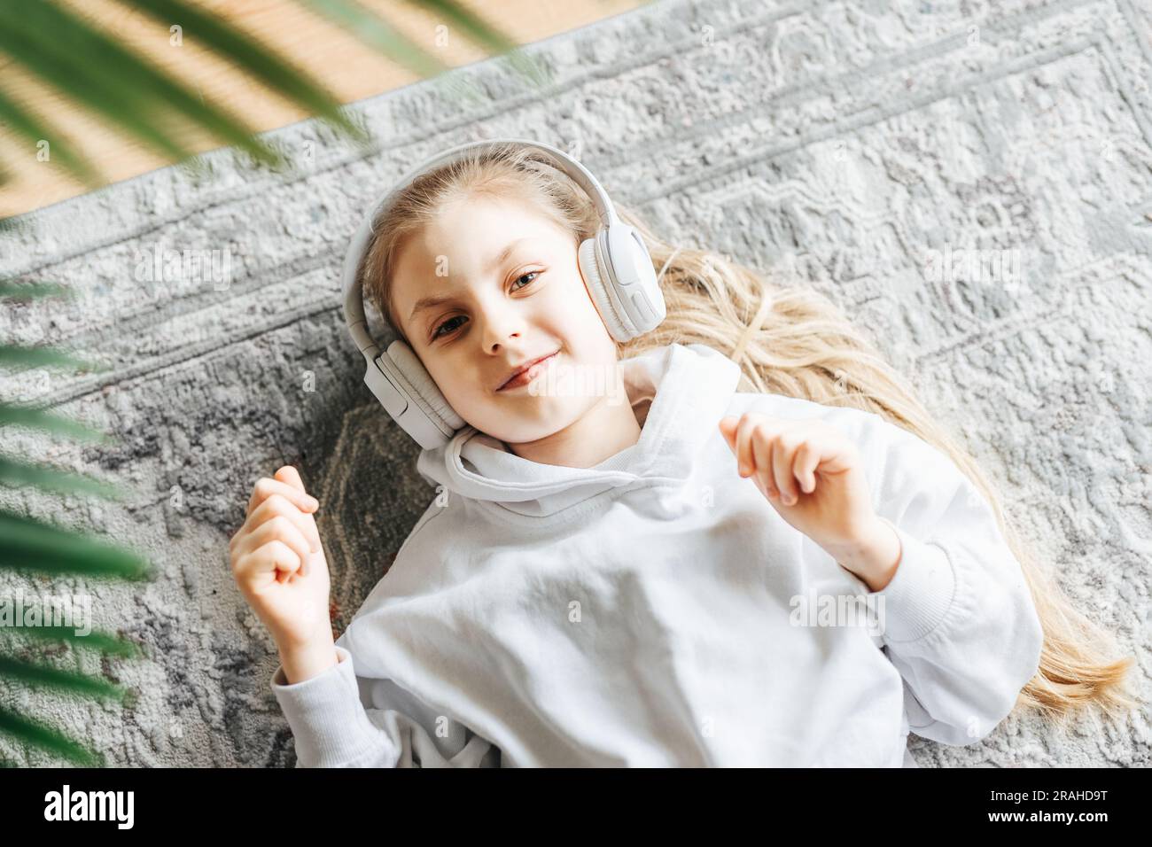 Smiling little girl listening music lying on the floor Stock Photo - Alamy