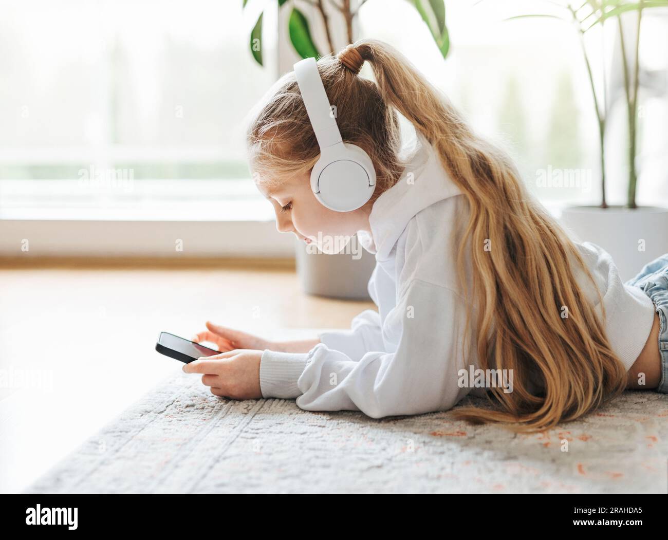 Smiling little girl listening music lying on the floor Stock Photo - Alamy
