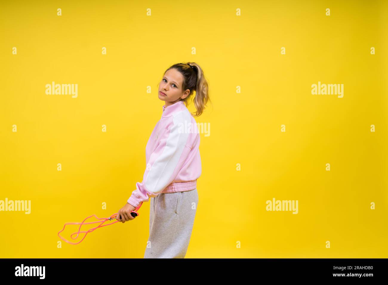 Beautiful sportsgirl with skipping rope isolated on yellow studio Stock