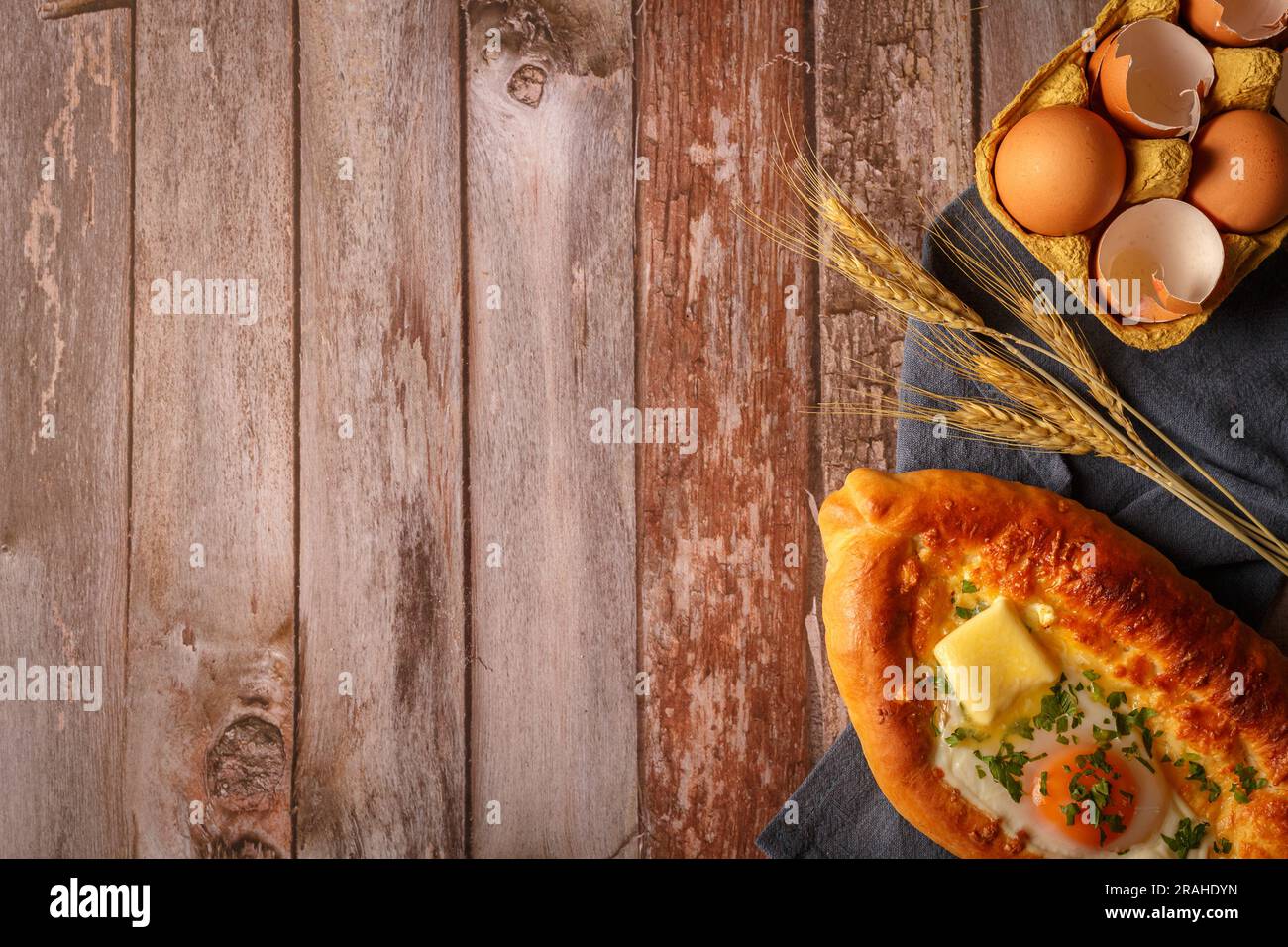 Adjarian Khachapuri is a traditional Georgian dish of sulguni cheese-filled bread with egg yolk. Top view. Copy space. Stock Photo