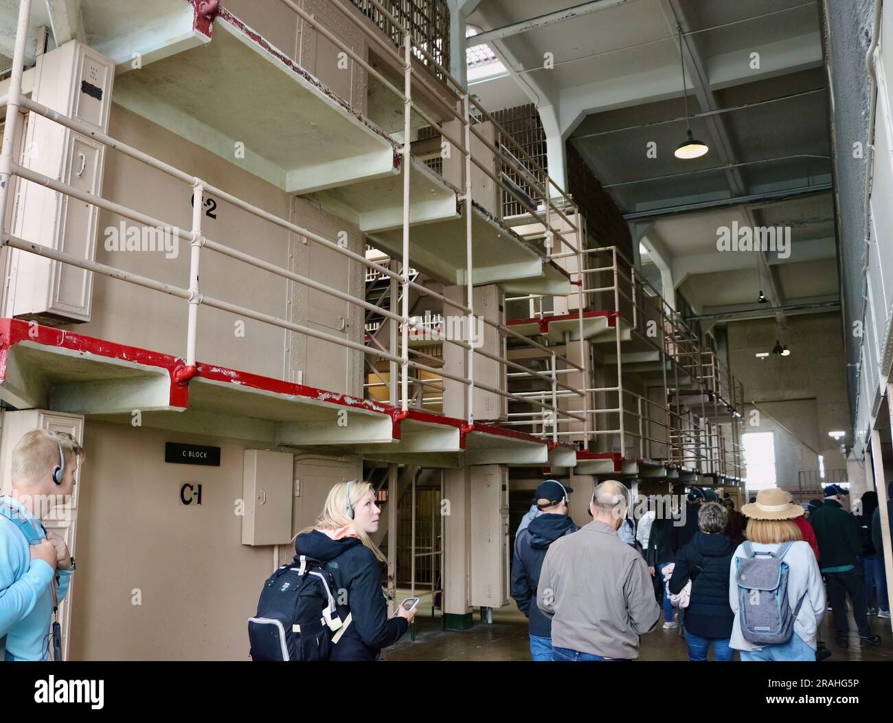 Tourists inside Alcatraz Federal penitentiary looking up at corridors with prison cells Alcatraz Island San Francisco California USA Stock Photo