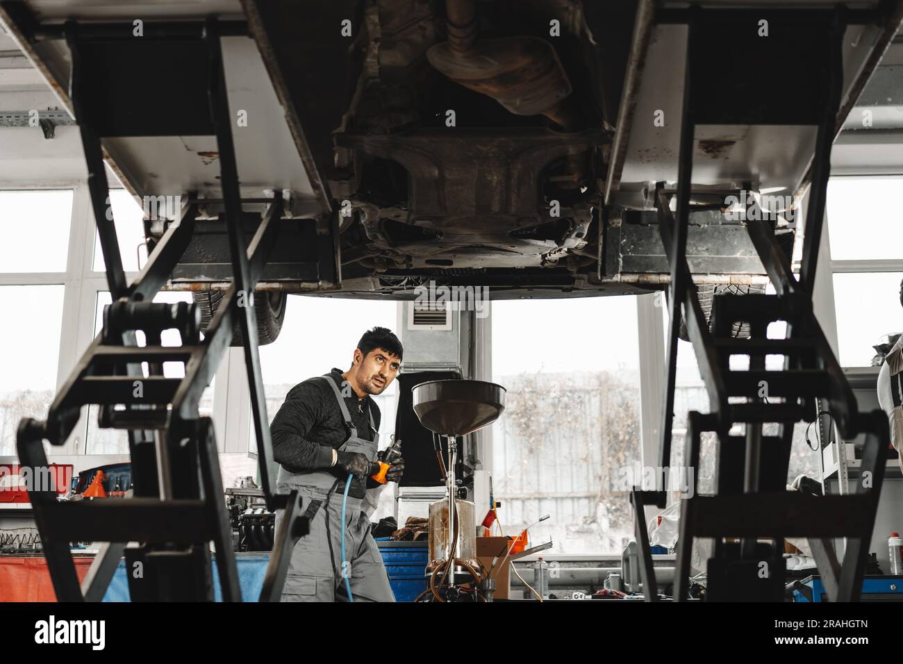 Workman mechanic working under car in auto repair shop Stock Photo - Alamy