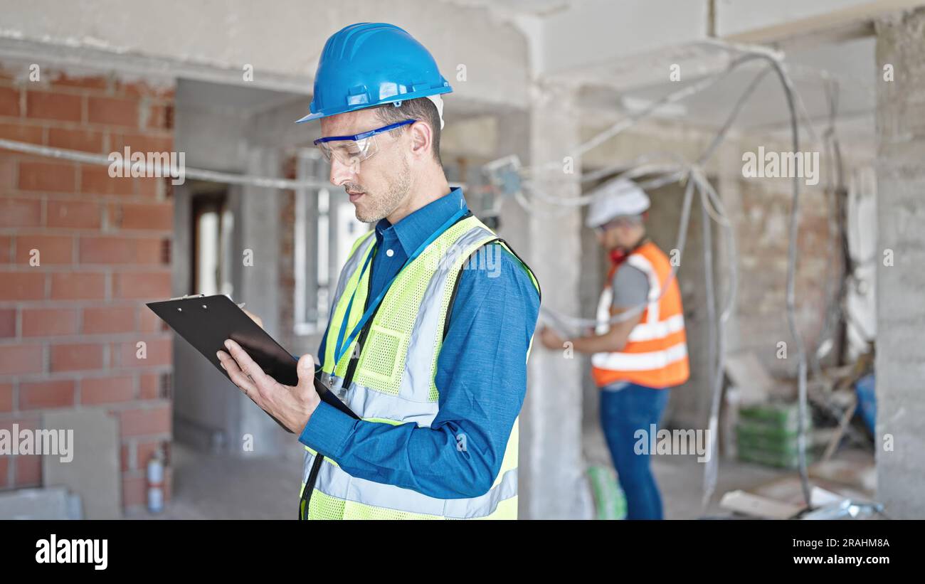 Two men builders writing document working at construction site Stock Photo
